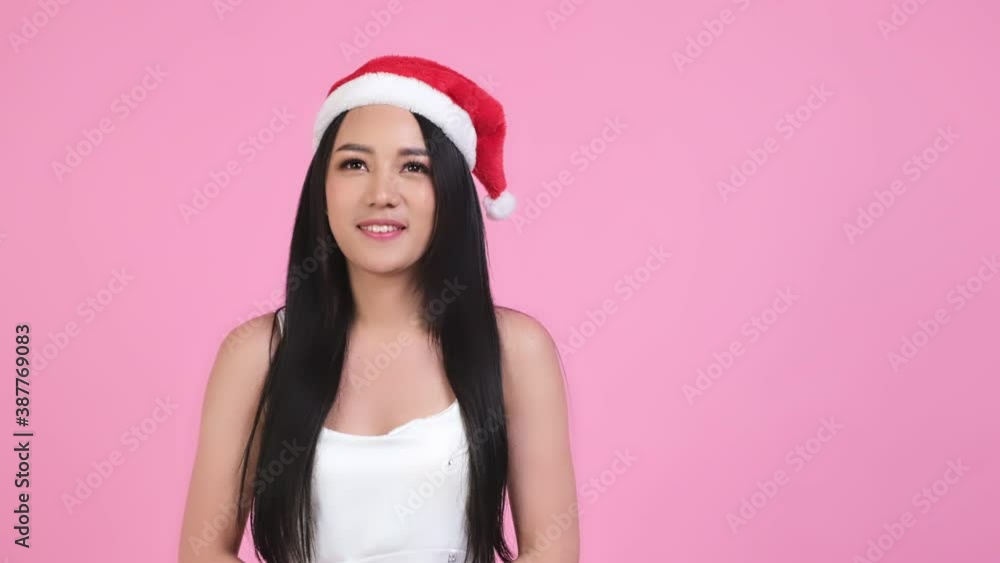 Cute asian women in christmas hats looking at camera isolated over pink background.young asian woman smile in christmas, new year, valentine day, birthday celebration concept.she play with confetti. Cute asian women in christmas hats looking at camera isolated over pink background.young asian woman smile in christmas, new year, valentine day, birthday celebration concept.she play with confetti.