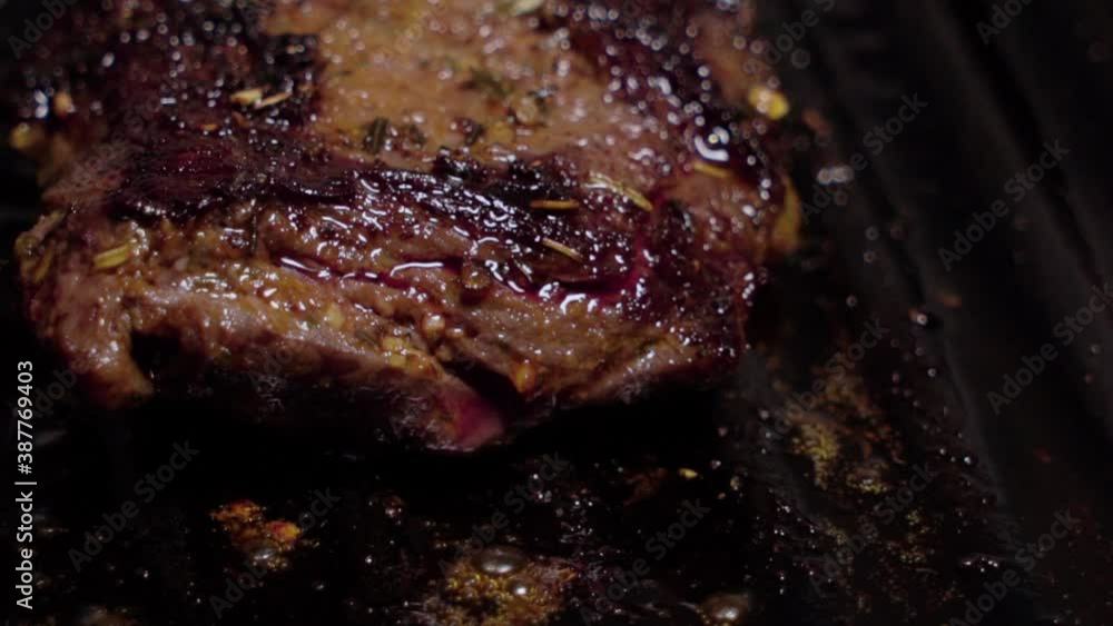 Grease bubbling from marinated beef steak cooking on cast iron griddle
