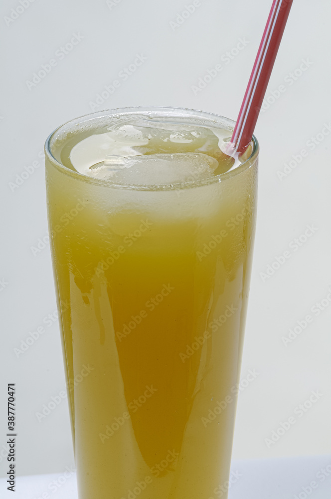 Brazilian gastronomy. Glass cup with cane juice and plastic straw, on white background. Traditional cheap drink, widely consumed throughout Brazil. Brazilian gastronomy. Glass cup with cane juice and plastic straw, on white background. Traditional cheap drink, widely consumed throughout Brazil.