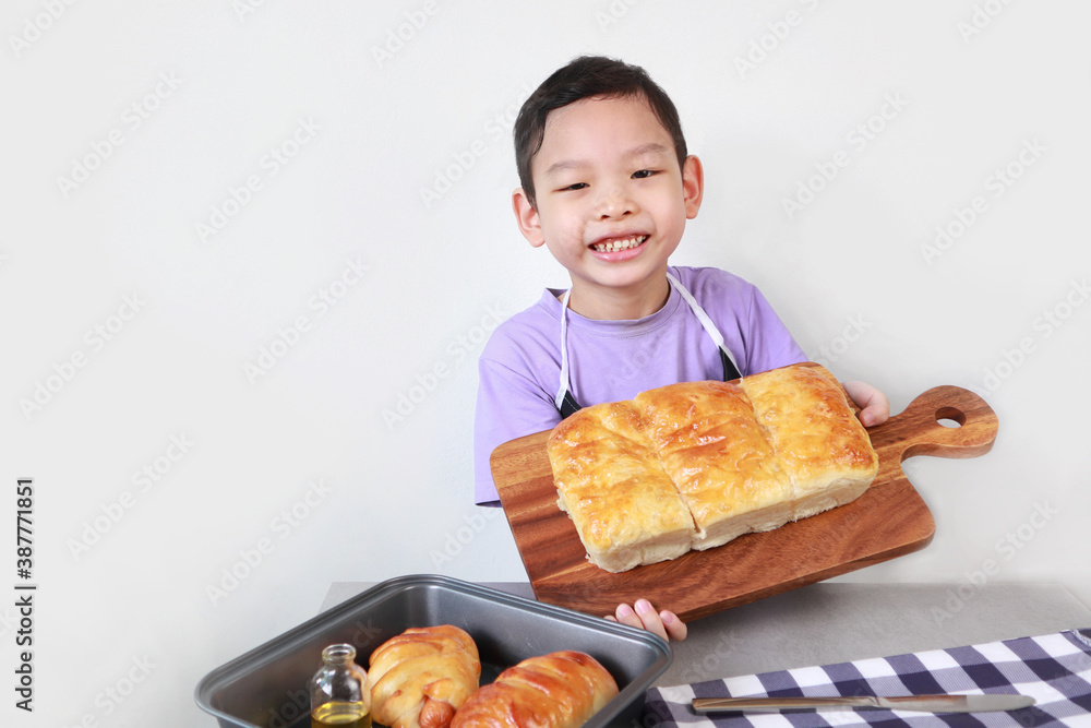 an asian black short hair kid boy is making his own sweet butter bread during the learning bakery class in the kitchen with white cement wall back ground an asian black short hair kid boy is making his own sweet butter bread during the learning bakery class in the kitchen with white cement wall back ground