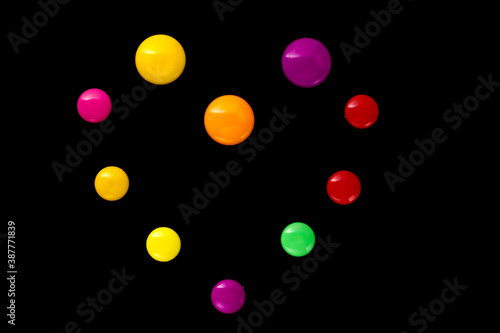 The shape of the heart is made of colored plastic magnets on a black background  top view .