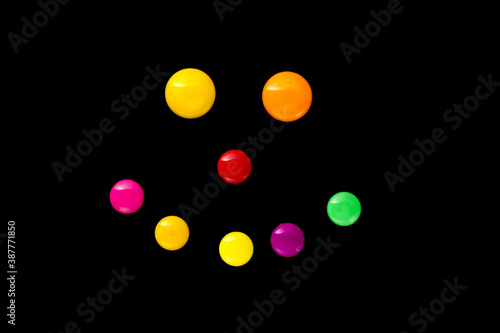 The outline of a smile is made of colored plastic magnets on a black background (top view).