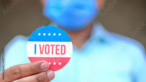 Obraz na plátně Man from minority group holds I Voted sticker upclose to the camera rackfocus