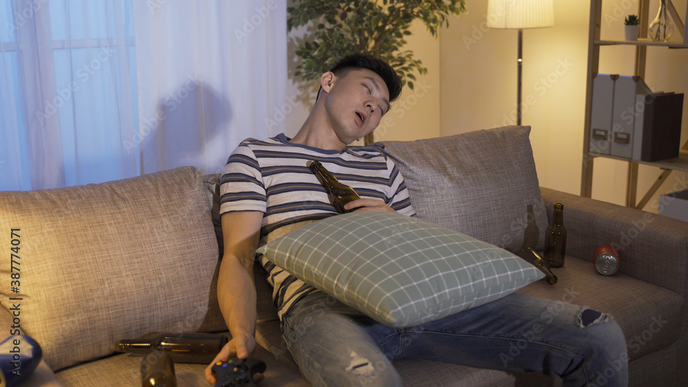 exhausted asian chinese guy gamer playing game until late night and