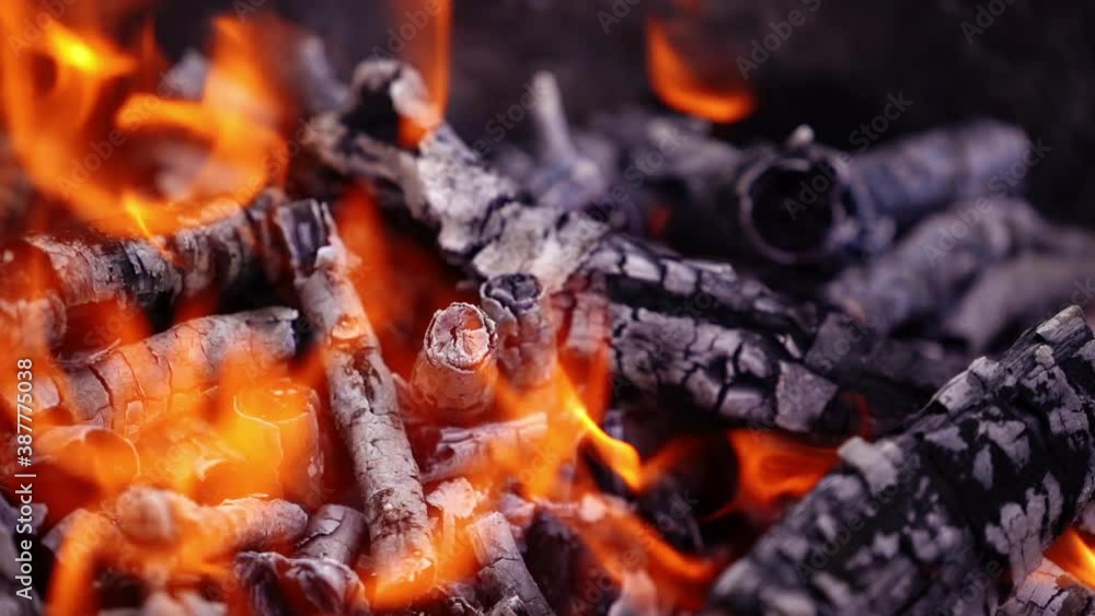 Smoldered wooden logs background. White ash from wood in fire. Detailed motion of slight flame over the charcoals. Close-up. Slow motion. Smoldered wooden logs background. White ash from wood in fire. Detailed motion of slight flame over the charcoals. Close-up. Slow motion.