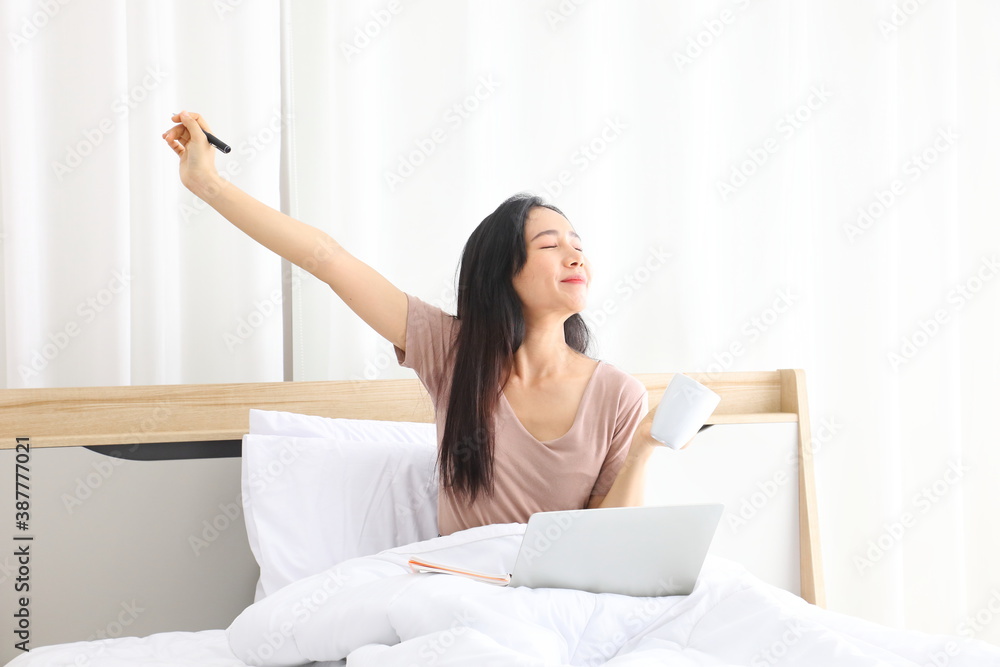 Asian woman stretching after working from home using laptop computer while drinking coffee with copy space Asian woman stretching after working from home using laptop computer while drinking coffee with copy space