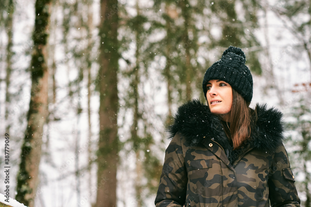 Seasonal outdoor portrait of happy young woman enjoying nice sunny day in winter forest