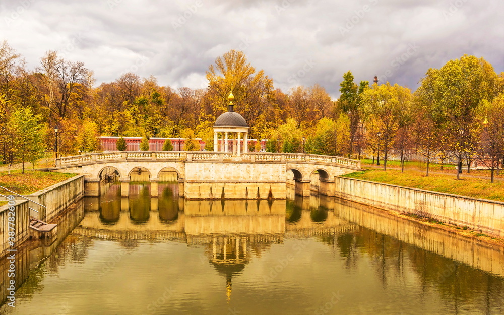 Bridge with  chapel over  lake in an autumn park