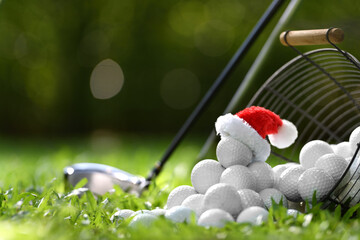 Festive-looking golf ball on tee with Santa Claus' hat on top for holiday season on golf course background..