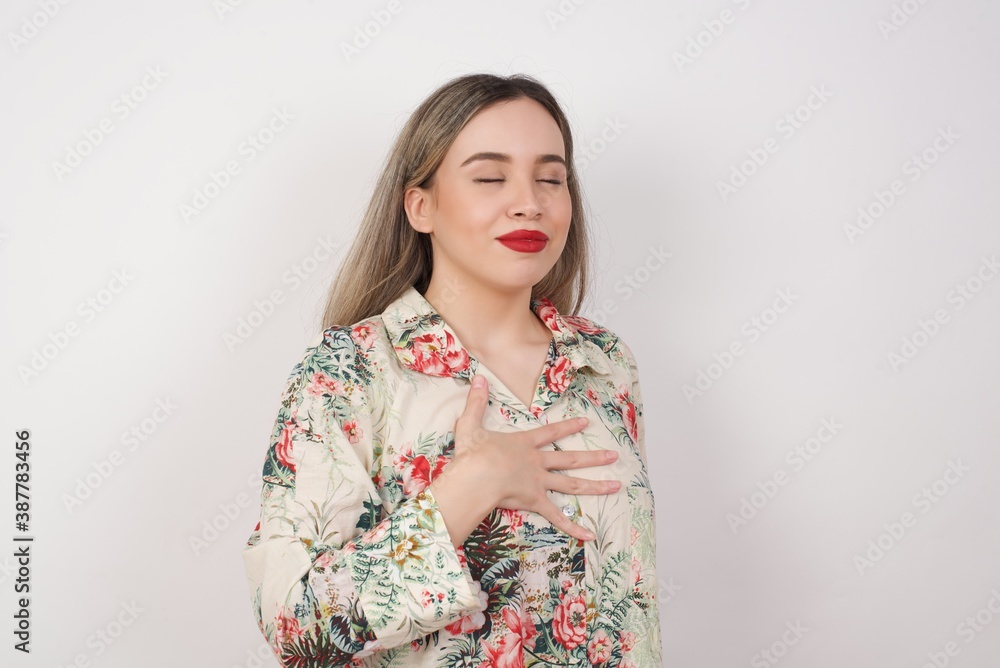 Satisfied smiling young woman isolated over background, keeps hands on belly, being in good mood after eating delicious supper, demonstrates she is full. Pleasant feeling in stomach. Satisfied smiling young woman isolated over background, keeps hands on belly, being in good mood after eating delicious supper, demonstrates she is full. Pleasant feeling in stomach.