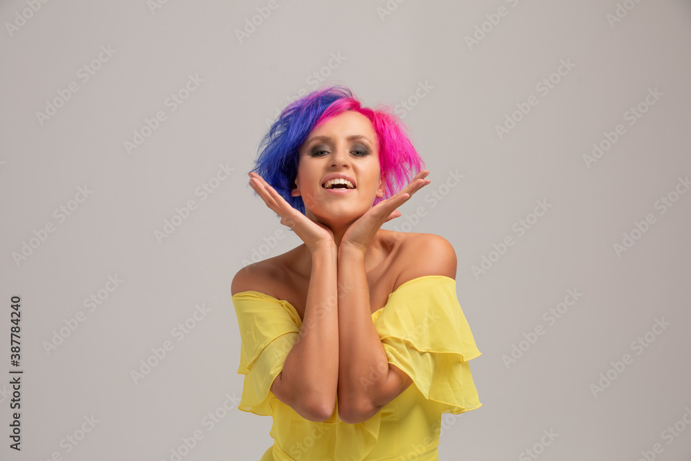 Portrait of a woman with bright colored hair, blue and pink haircut. girl with short hair dressed to yellow dress with open shoulders