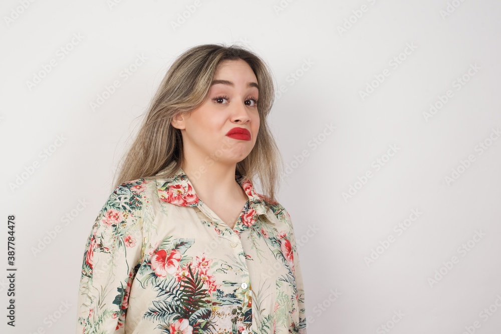 Beautiful woman standing against orange background, with snobbish expression curving lips and raising eyebrows, looking with doubtful and skeptical expression, suspect and doubt. Beautiful woman standing against orange background, with snobbish expression curving lips and raising eyebrows, looking with doubtful and skeptical expression, suspect and doubt.