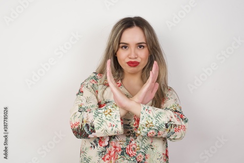 Young beautiful brunette girl wearing casual clothes standing over isolated background. Has rejection angry expression crossing hands doing refusal negative sign.