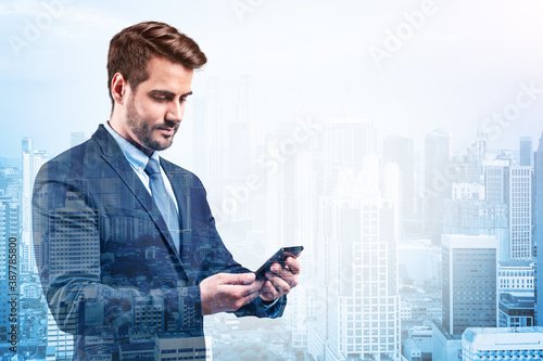 Prosperous European businessman in suit texting phone the details of corporate meeting. Kuala Lumpur cityscape. The concept of business communication. KL skyscrapers. Double exposure. photo