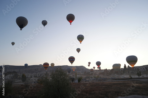Hot air balloons flying over rocky landscape. Ballooning at Goreme National Park. Cappadocia, Turkey.