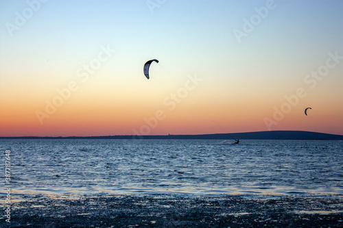 Kitesurfing against the sky at sunset. Riding the waves. Kites in the sky above the sea.