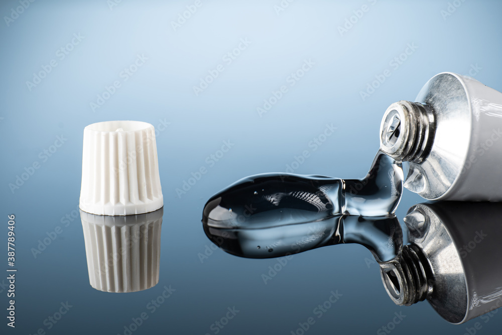 ointment or gel for external use is slightly squeezed out of the tube next to the cap on a gradient background with reflection ointment or gel for external use is slightly squeezed out of the tube next to the cap on a gradient background with reflection