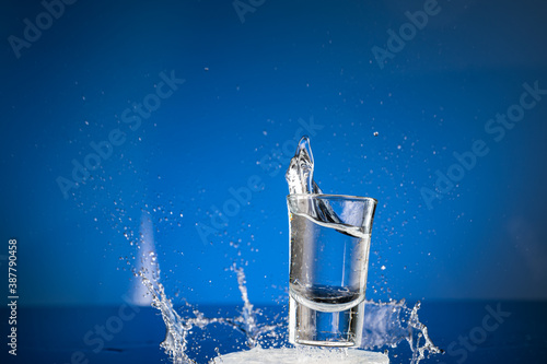 splash from falling glasses with water on blue background