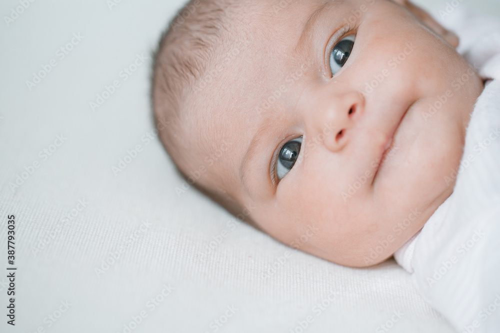 Adorable baby in a white sunny bedroom. Newborn baby is resting in bed. Family morning at home. Adorable baby in a white sunny bedroom. Newborn baby is resting in bed. Family morning at home.