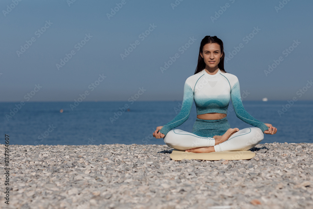 Caucasian young woman practicing yoga at seashore
