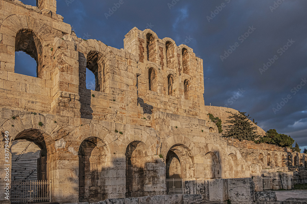 Picturesque view of Greek ruins of Odeon of Herodes Atticus (161AD) - stone Roman theater at the Acropolis hill on sunset. Athens, Greece.