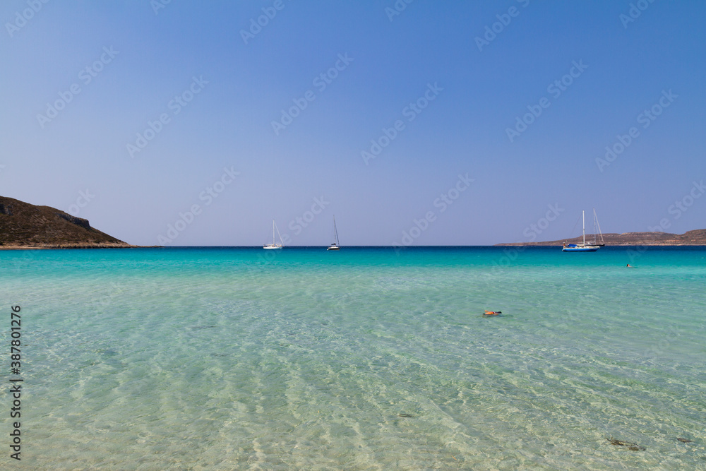 Simos bay at Elafonissos, south Greece. 
A peacefull scenery with turquoise water and blue sky. A few sailing boats in the horizon. Wide angle photo with clear depth of view