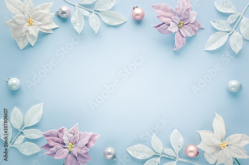 Christmas arrangement with festive baubles  poinsettia flowers and silver leaves on pastel background. Flat lay. Top view  copy space.