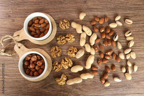 various nuts are scattered on a wooden background. nuts in white plates