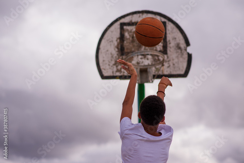 Rear view of young boy shooting basketball towards hoop