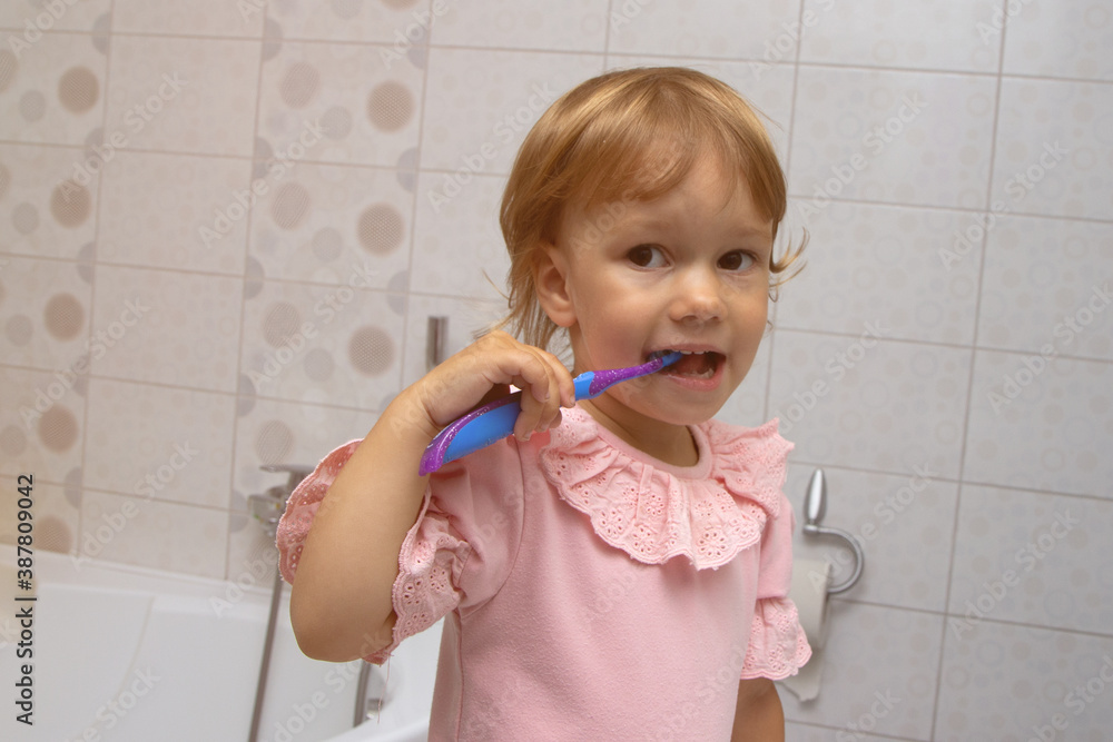 Little girl in pink pyjamas in bathroom brushing teeth Little girl in pink pyjamas in bathroom brushing teeth