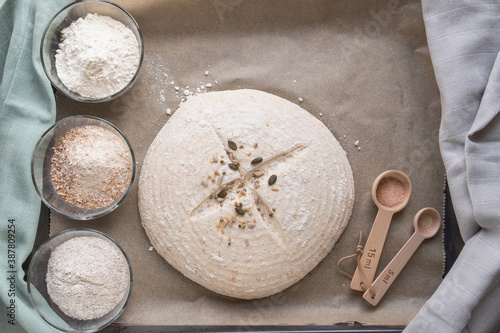 ingredients to bake homemade sourdough: rye, wholegrain, plain wheat flour, arranged on baking paper, shot from above