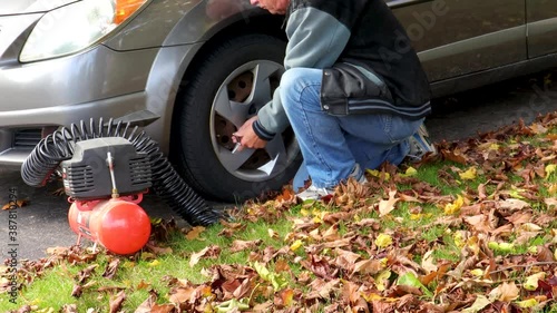 A man checks the car's tire pressure, adds too much air and releases the excess. photo