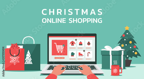 Christmas online shopping concept, human hand makes order on laptop screen with gift boxes, shopping bags on the desk, and text, winter holidays sales, vector flat illustration