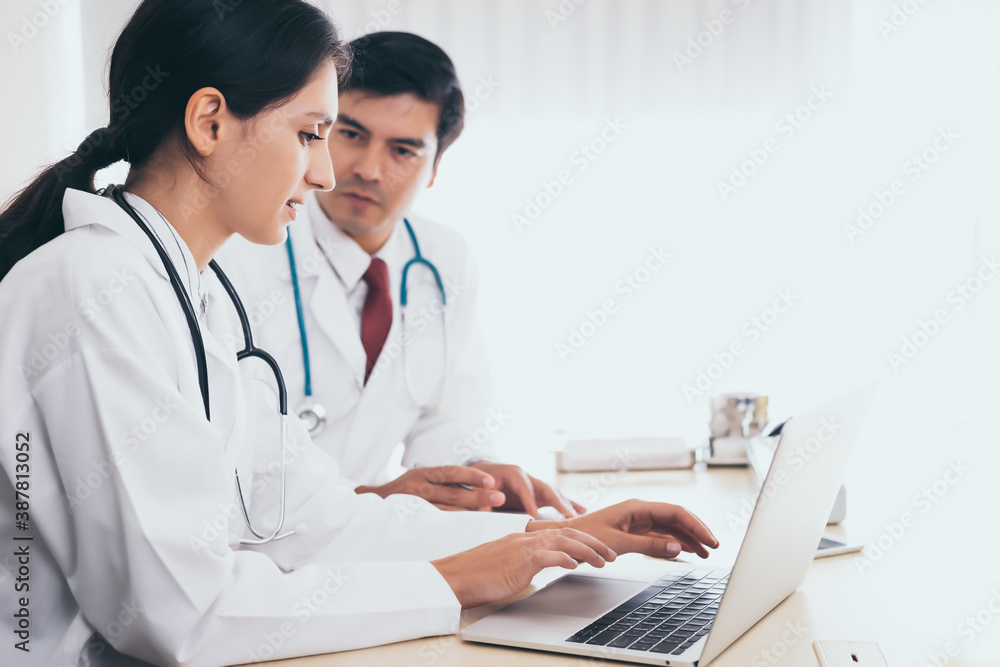 Doctors team discussing patient case, sitting in doctors office and working on laptop computer. Doctor woman working with laptop computer and doctor man telling about patient case. good teamwork Doctors team discussing patient case, sitting in doctors office and working on laptop computer. Doctor woman working with laptop computer and doctor man telling about patient case. good teamwork