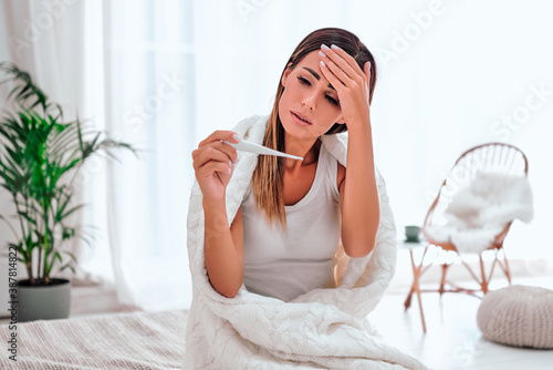 Sick young woman at home on the bed  she is covering with a blanket.