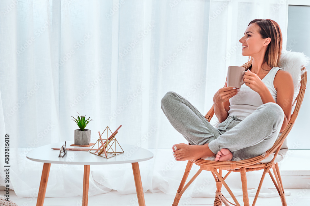 Young girl sitting in modern chair, enjoying coffee In front of window. Young girl sitting in modern chair, enjoying coffee In front of window.