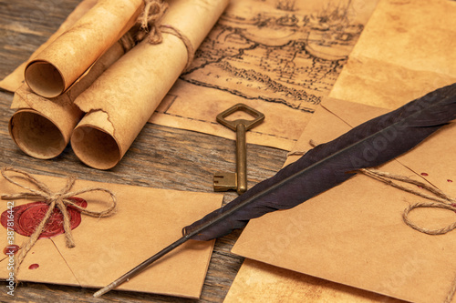 The surface of the old wooden table. On the table are old scrolls, an old map, an envelope with a seal, an iron key to the lock.