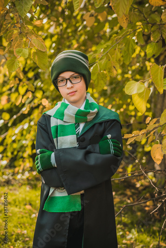 Kid wizard. A young student of the magic school conjures. Boy in green robe magic in the forest. Halloween time