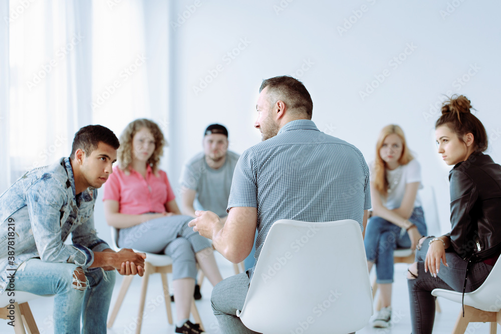Professional Therapist with group of rebellious teenagers during psychotherapy session Professional Therapist with group of rebellious teenagers during psychotherapy session