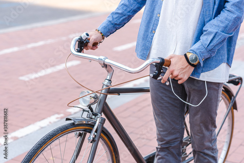 retro style urban bicycle being held by an unrecognizable young caucasian man in casual clothes near a bike path in a city