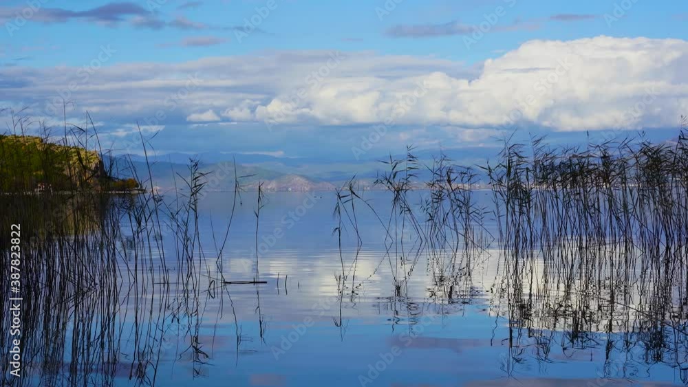 Peaceful lake with calm water and birds flying on mountains and white clouds background Peaceful lake with calm water and birds flying on mountains and white clouds background