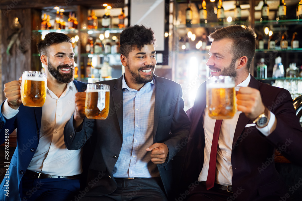 Young businessmen are drinking beer, talking and smiling while resting at the pub
