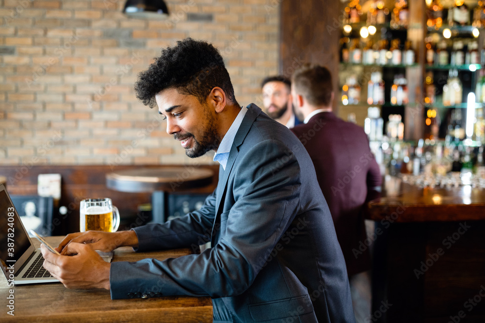 Handsome young business man, blogger or remote working with laptop in bar