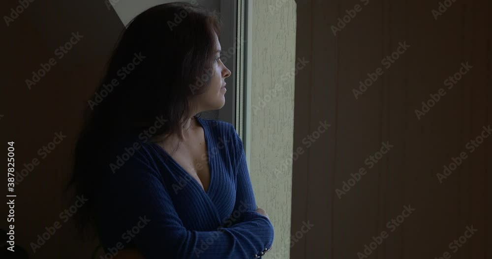 Sad Thoughtful Woman Stands Thinking Waiting. Looking out the Window on Backyard. 4K Sad Thoughtful Woman Stands Thinking Waiting. Looking out the Window on Backyard. 4K