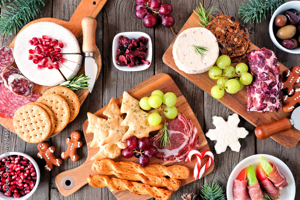 Christmas theme charcuterie table scene against a dark wood background. Assortment of cheese and meat appetizers. Top view. - obrazy, fototapety, plakaty 