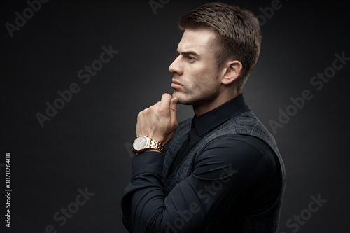 Portrait of beautyful guy on dark background. High fashion model posing in studio. Attractive man in classic suit.