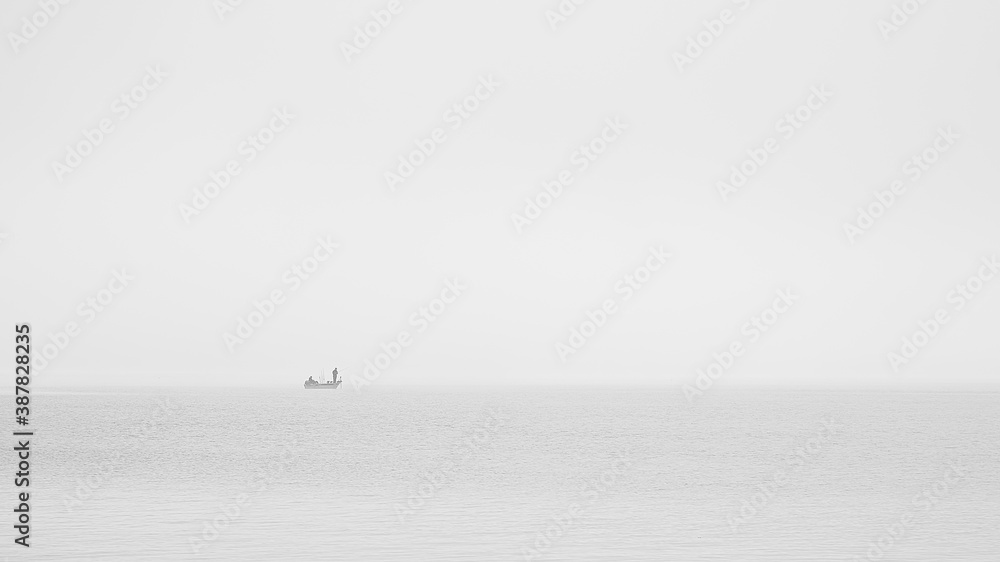 Landschaftsaufnahme eines Fischerboot auf einem nebeligen See