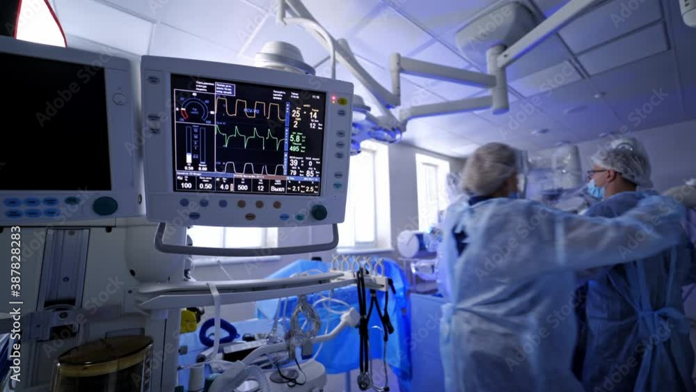 Heart rate monitor on robotic surgery background. Medical vital signs monitor in hospital. Group of doctors conduct surgery with new medical technologies.