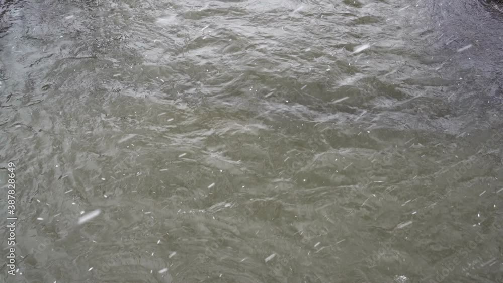 Top view of the river surface, where large flakes of white snow fall on a gloomy winter day. Bad weather. Winter landscape. 4K Top view of the river surface, where large flakes of white snow fall on a gloomy winter day. Bad weather. Winter landscape. 4K