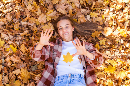 Portrait of a beautiful young woman on the background of autumn yellow leaves, outdoors